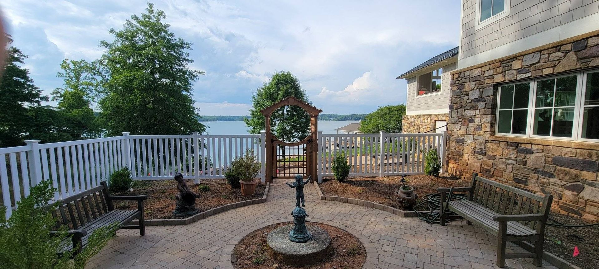 A courtyard with a fountain, benches, and a gate overlooking a body of water.