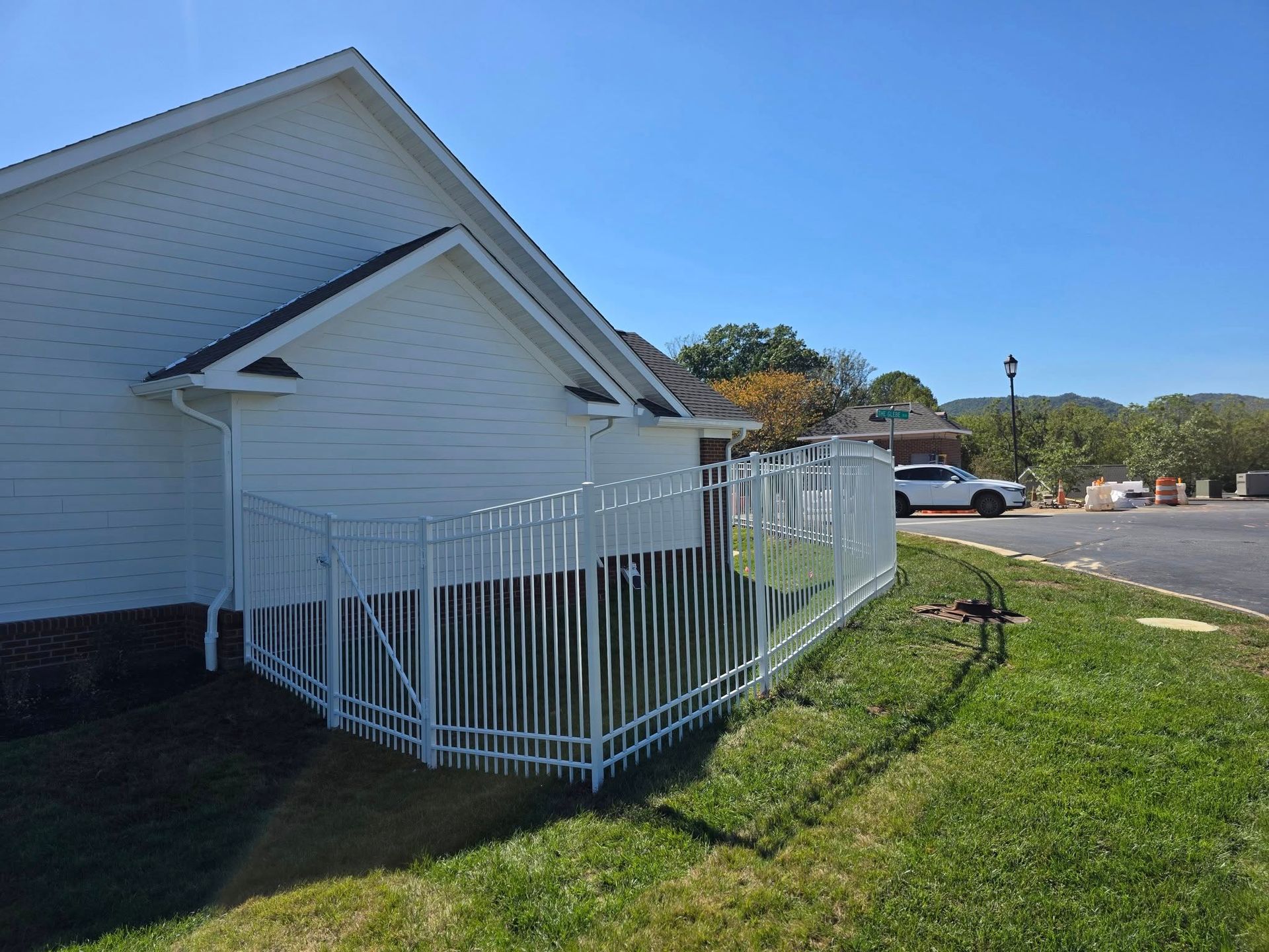 White building with white fence in front. Sunny day.
