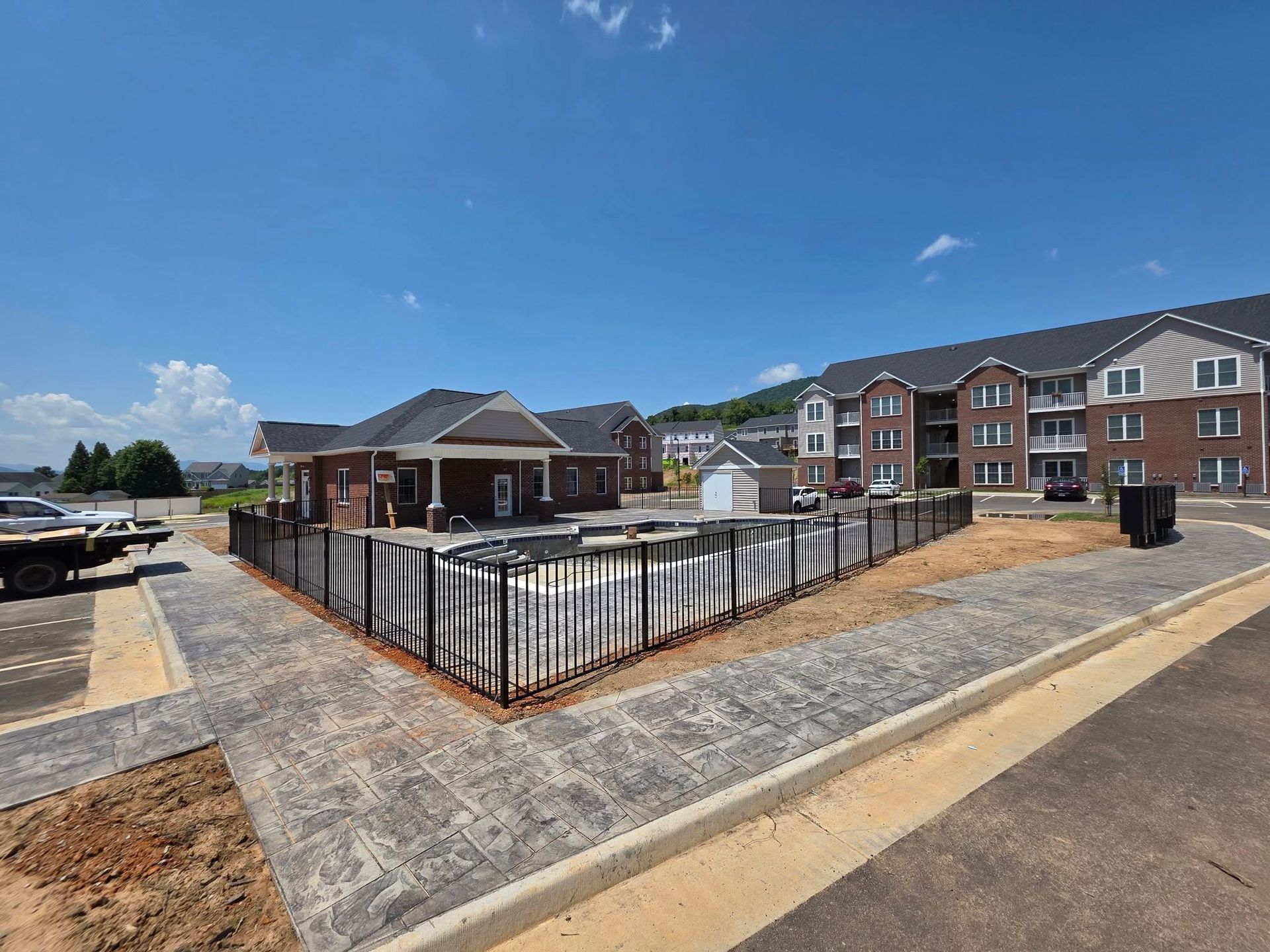 Apartment complex with pool area, brown brick buildings, blue sky.