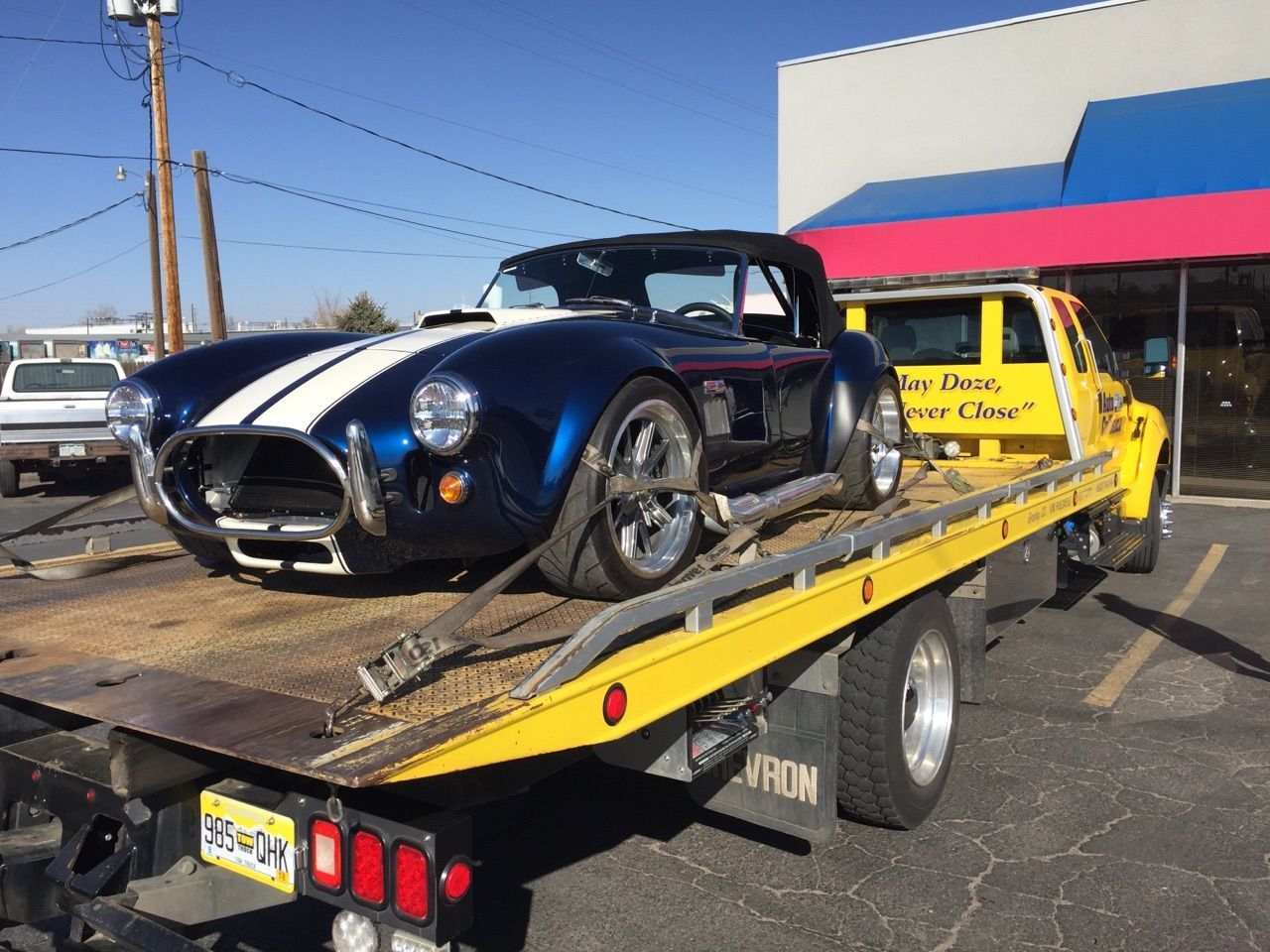 Blue and white Cobra sports car on a yellow tow truck.