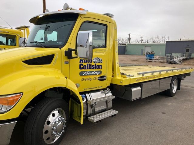 Yellow tow truck with "Auto Rite Collision" logo. Bright, sunny day.