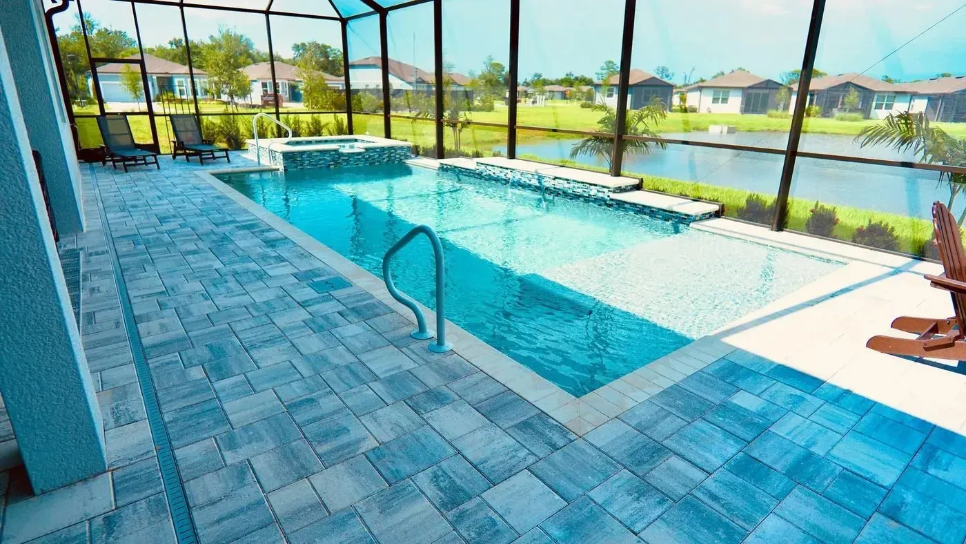 Screened-in backyard pool with blue tile deck and canal view beyond the fence