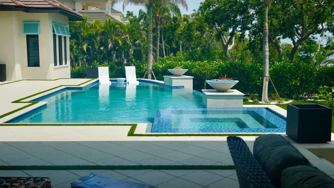 Modern backyard pool with turquoise water, white lounge chairs, and tropical garden landscaping