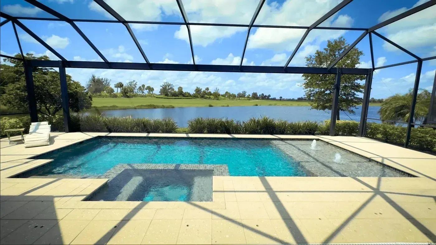 Screened-in patio with a swimming pool and lake view under a sunny blue sky