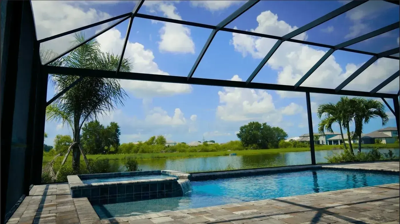 Screened patio with a pool overlooking a green lake under a blue sky