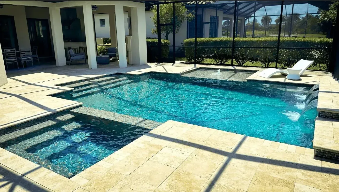 Backyard pool with turquoise water, stone patio, lounge chairs, and a covered patio beside it