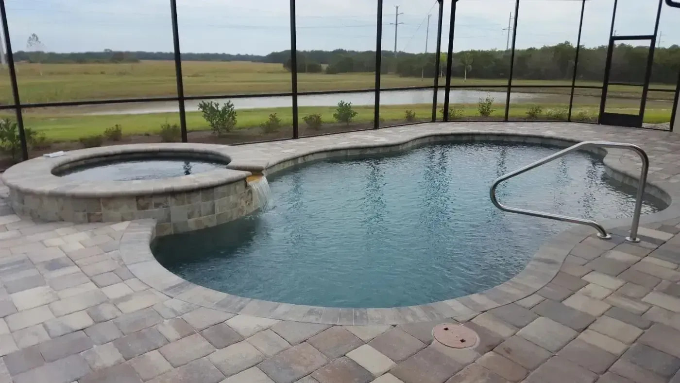 Backyard pool with built-in spa, stone deck, and screened enclosure overlooking open fields