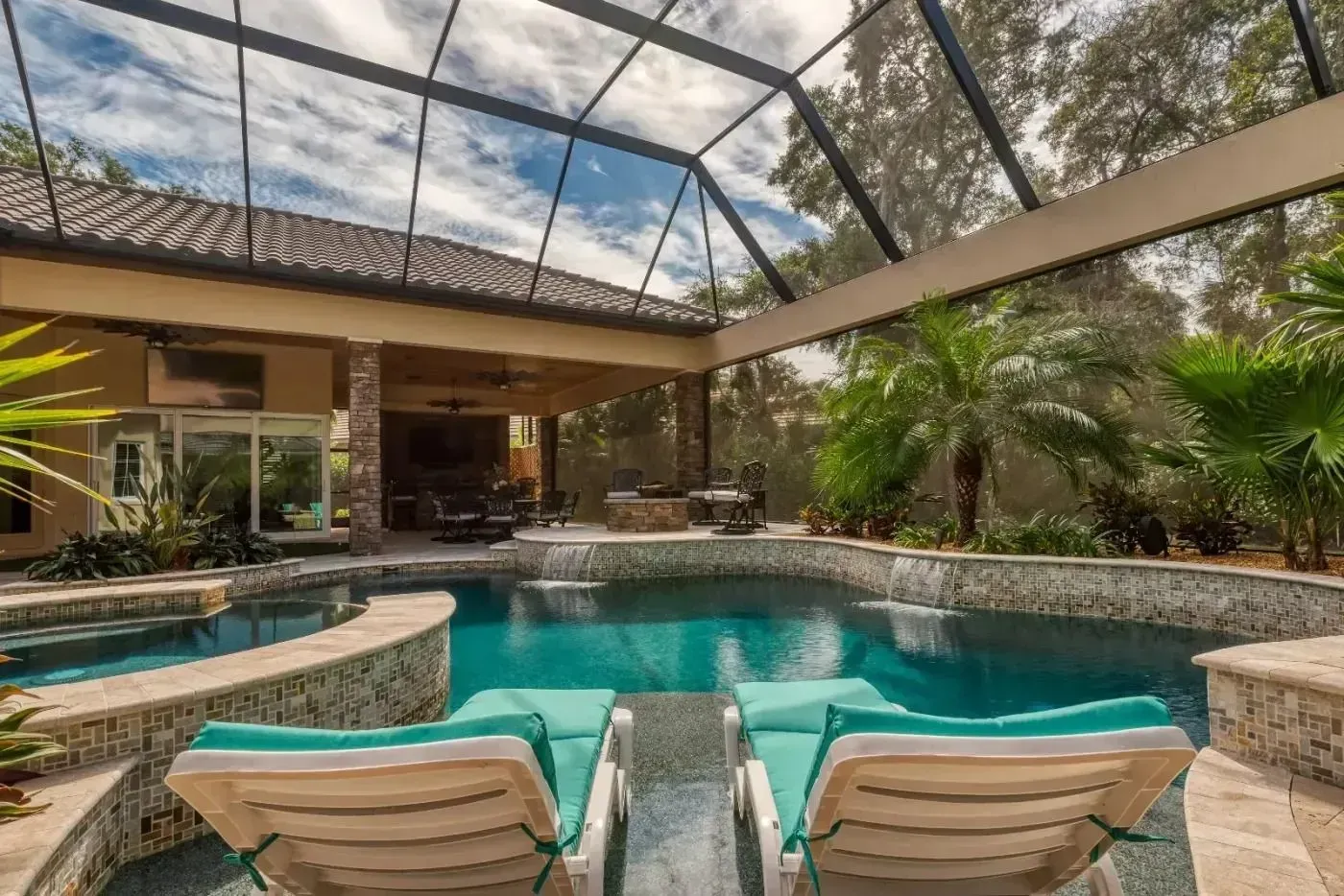 Screened-in patio with a turquoise pool, lounge chairs, and a house in the background