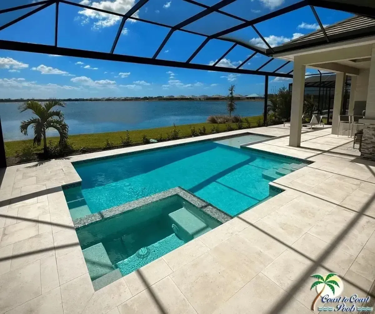 Modern backyard pool with spa, white patio, blue screen enclosure, and ocean view in the background