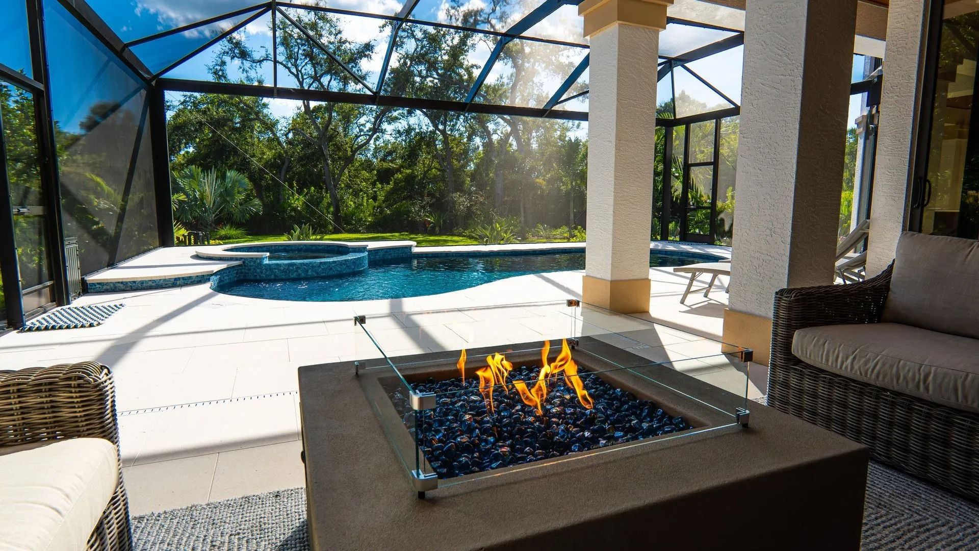 Screened patio with a fire pit and pool under bright sunlight