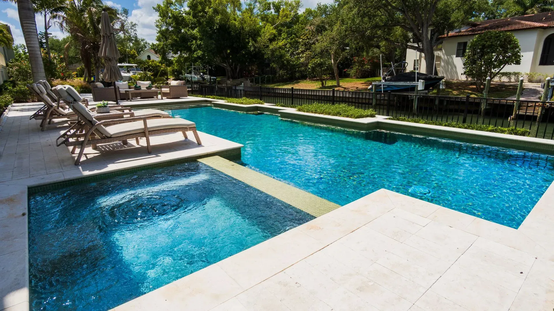 Resort pool with blue water, lounge chairs, and trees in bright sunlight