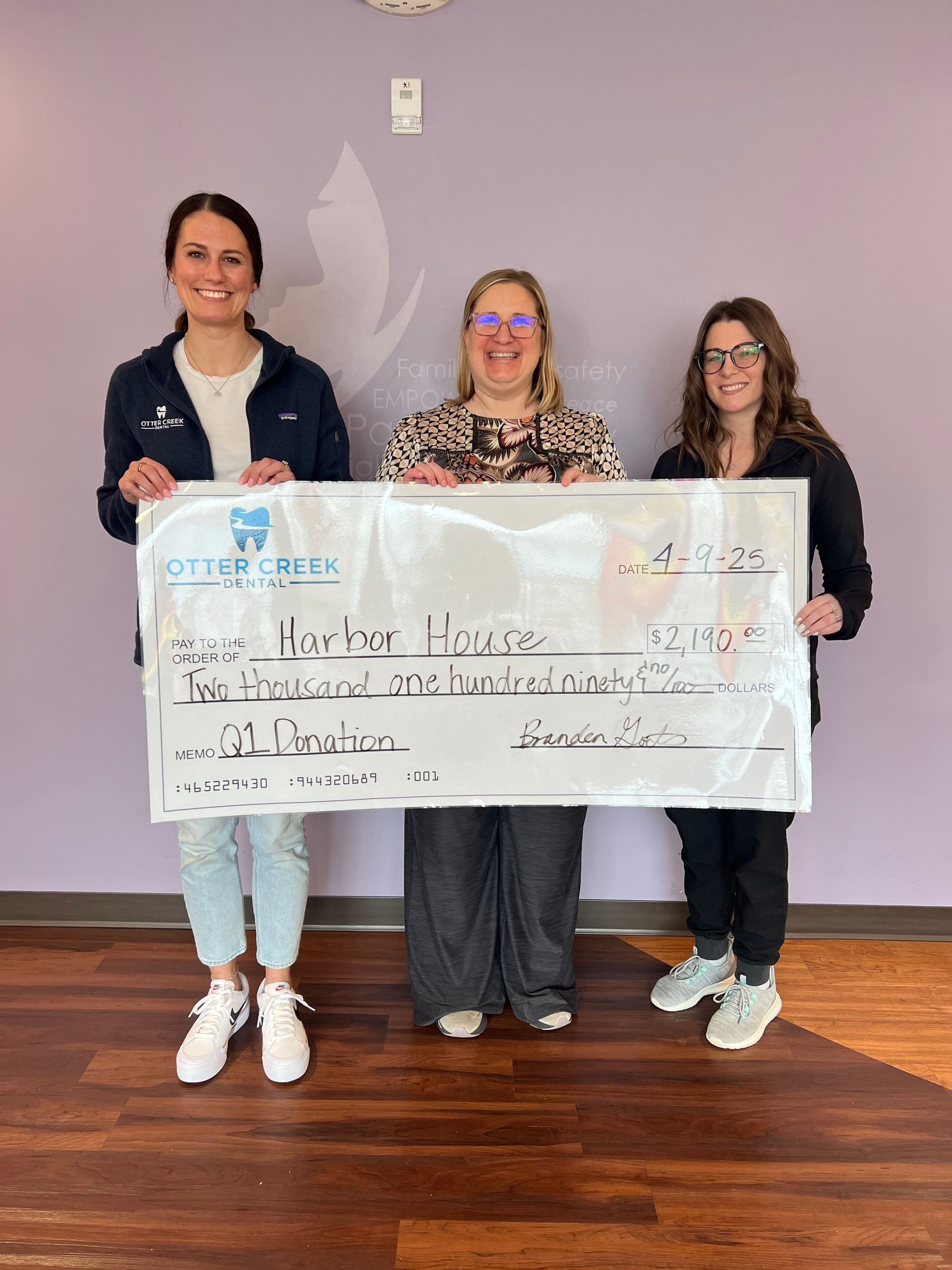 Three people holding a large check.