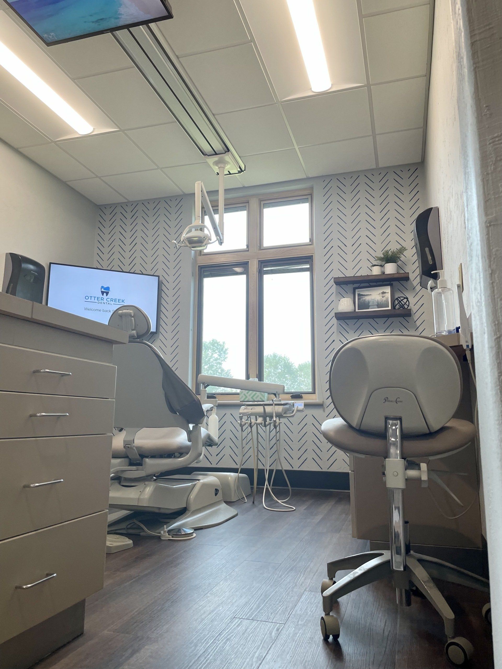 Dental office interior with dental chair, cabinets, window, and medical equipment.