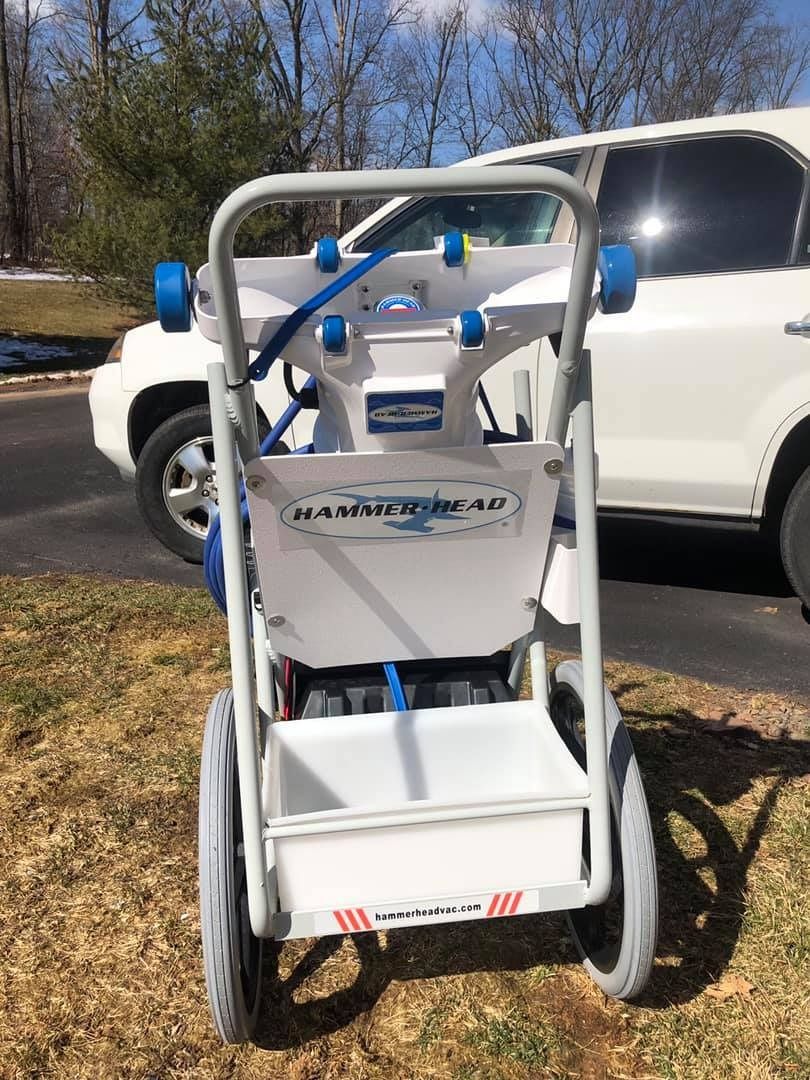 A white cart with blue accents and gray wheels, parked in front of a white SUV.