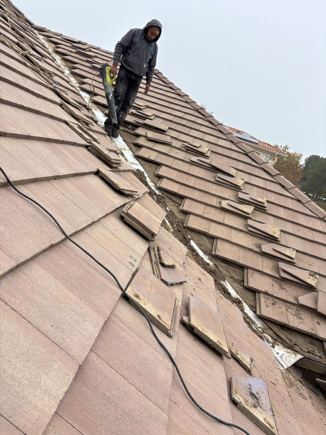 Person standing on a steep shingled roof during repairs or inspection