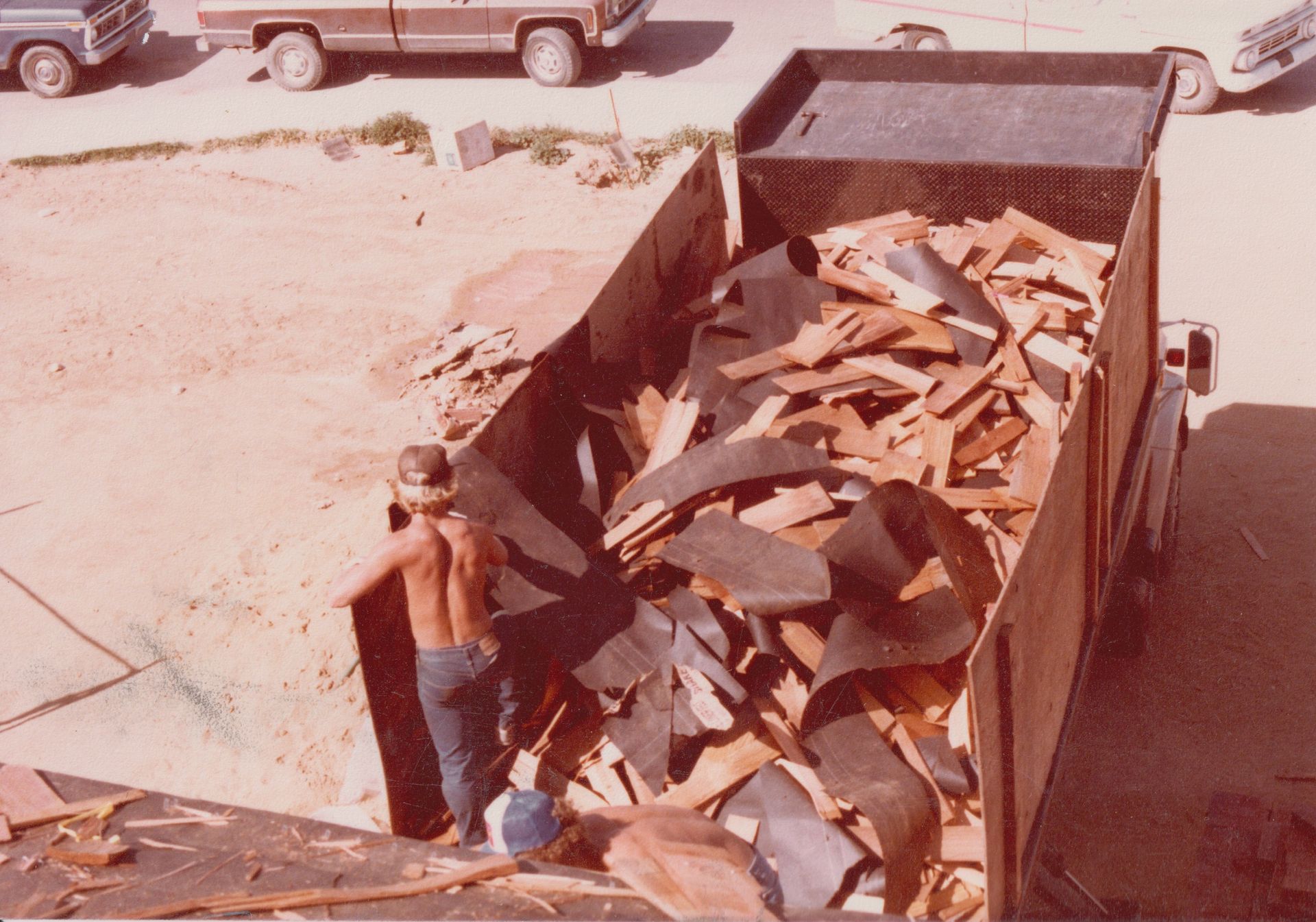 Worker loading broken concrete into a dumpster at a construction site