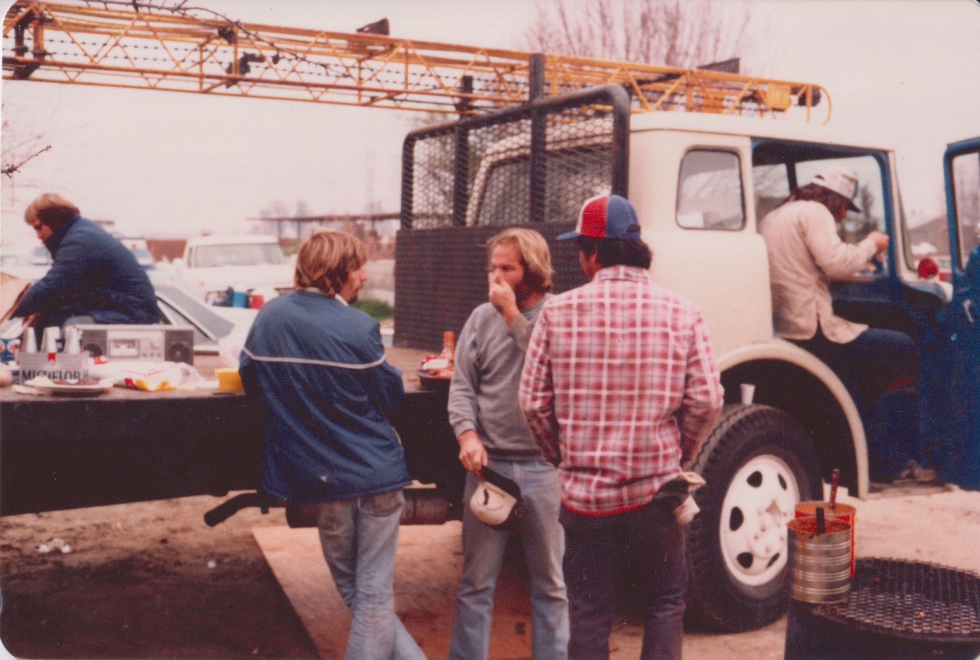 Workers standing by a truck on a construction site, with a crane in the background