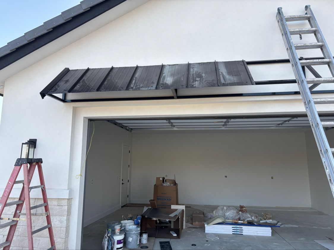 Garage under construction with ladders, tools, and unfinished exterior trim