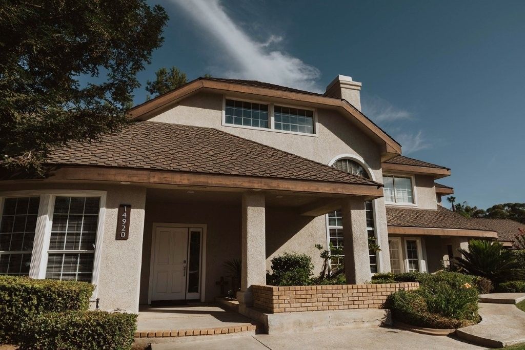 Spanish-style house with tiled roof, white stucco walls, and a front porch under a clear sky