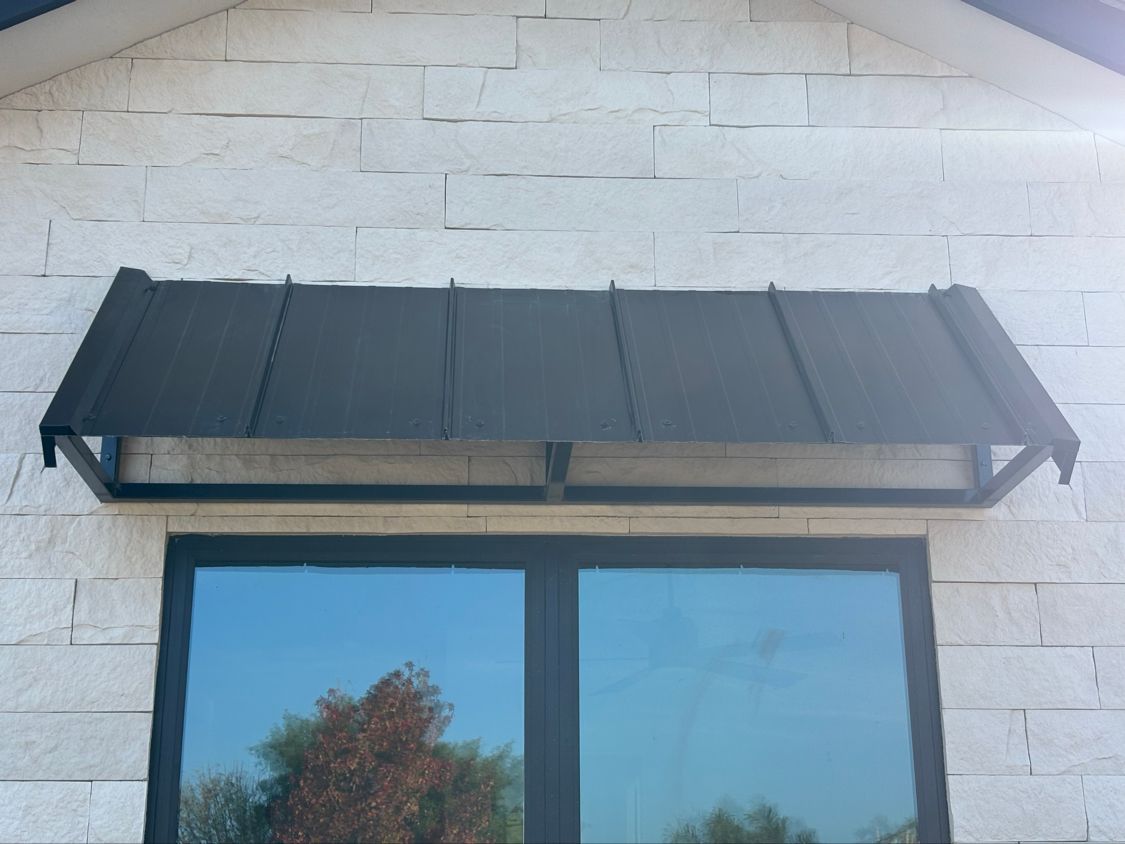 Black metal awning above a window on a white brick wall