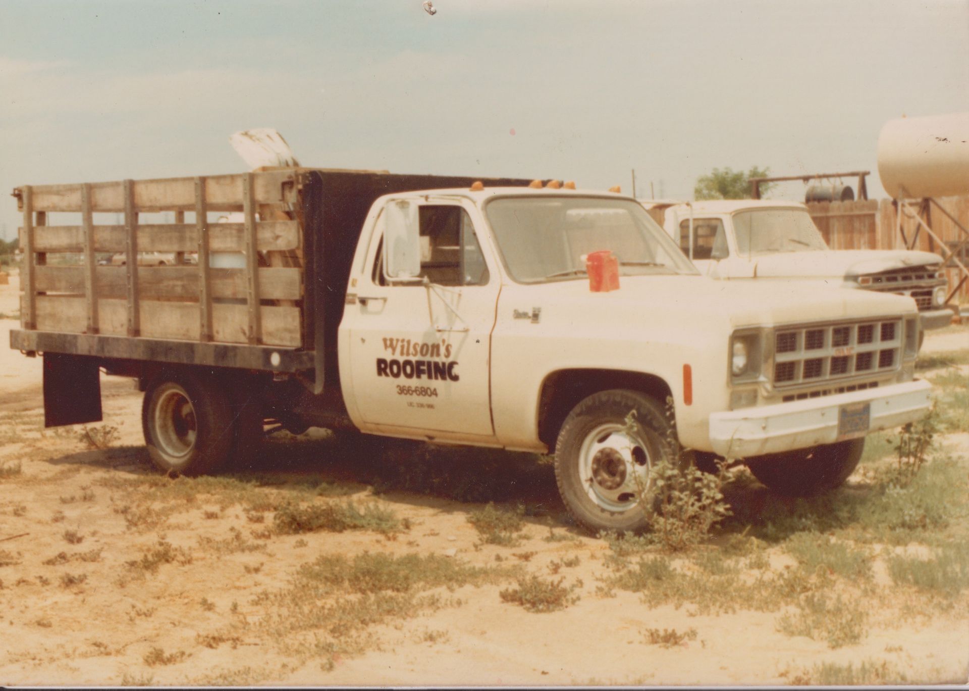 White dump truck parked on a dirt lot under a hazy sky.