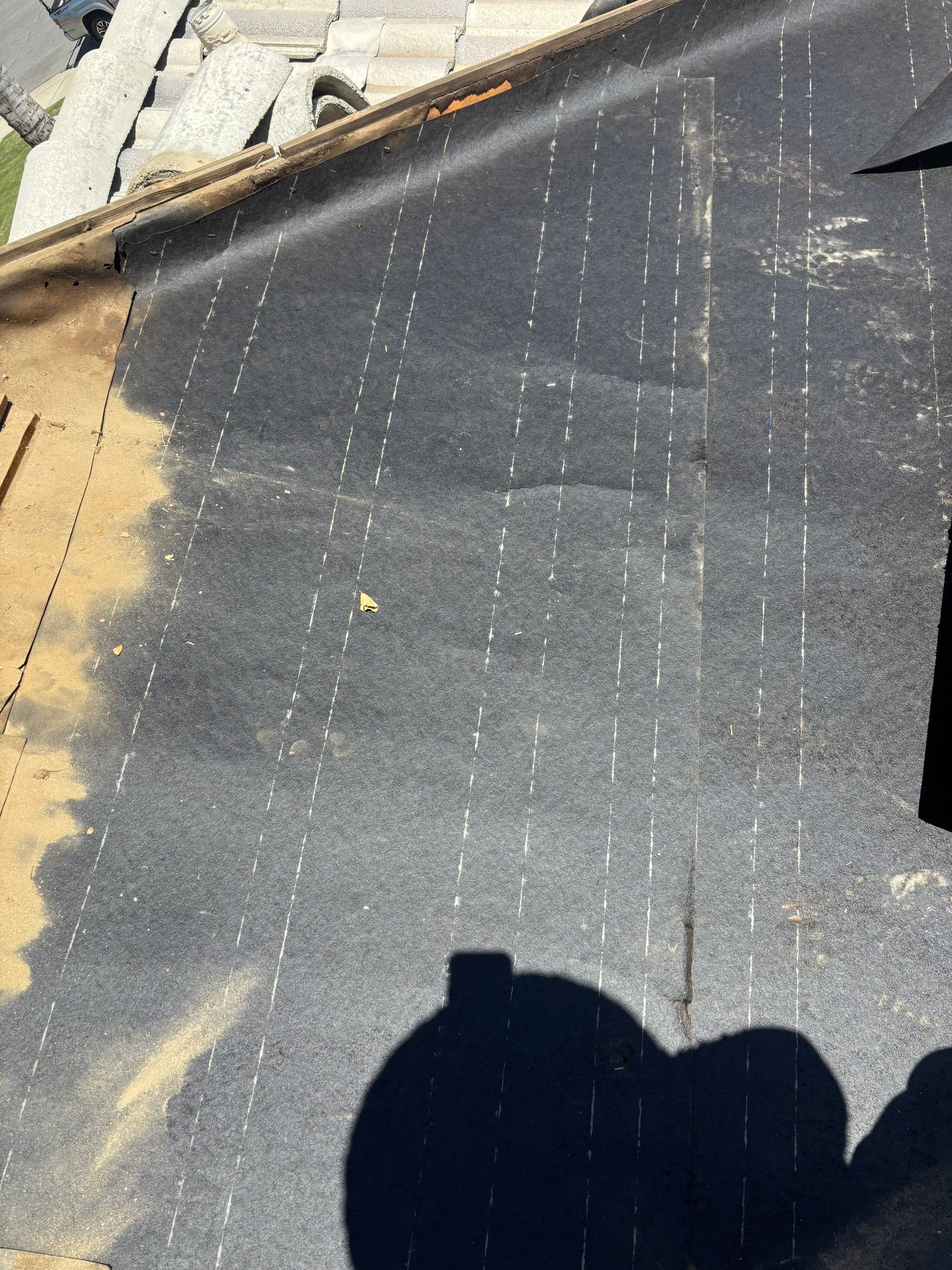 Dark roof surface with peeling white coating and a shadow at the bottom edge