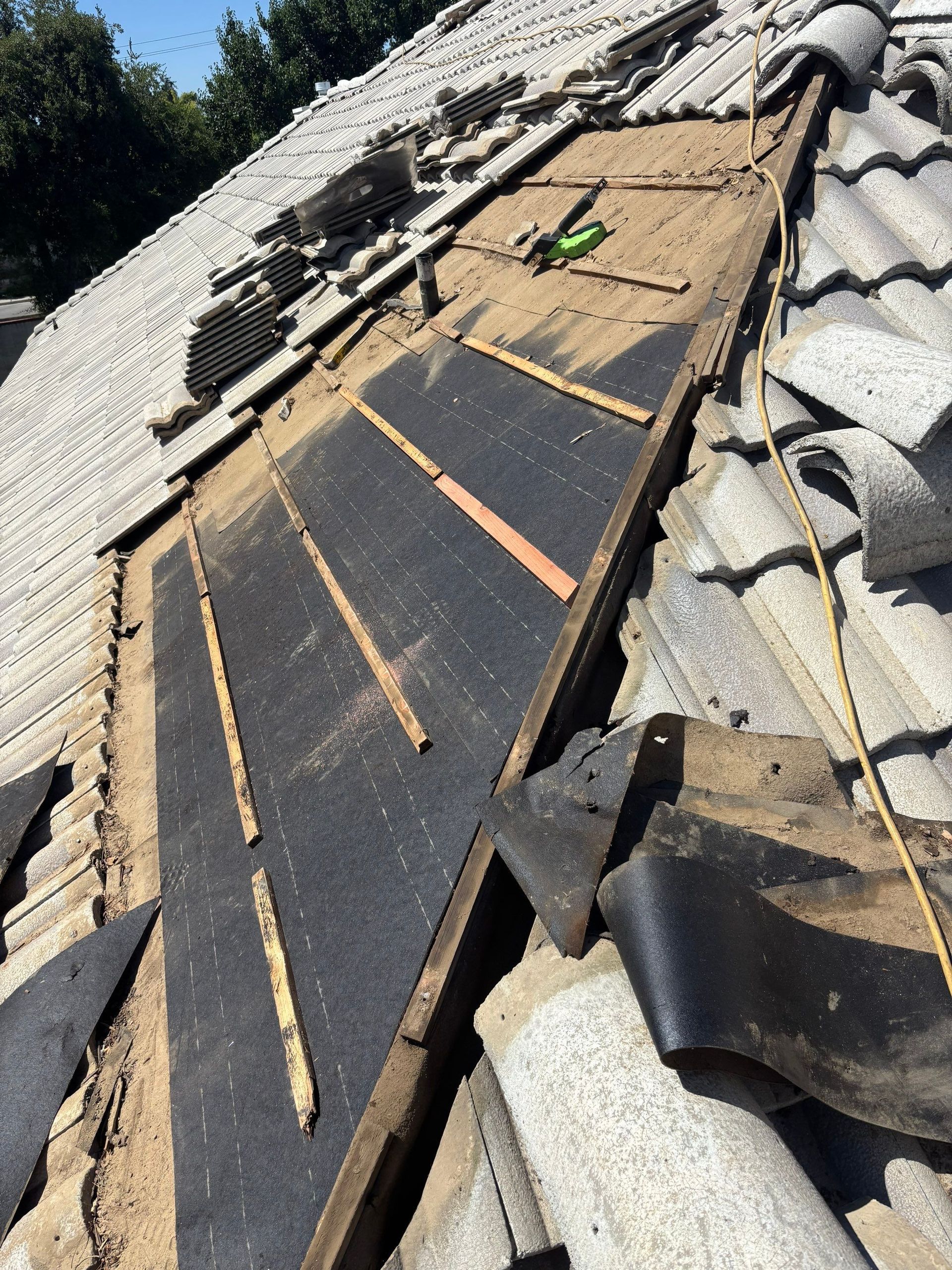 Roof damage with exposed underlayment and missing shingles on a sloped roof