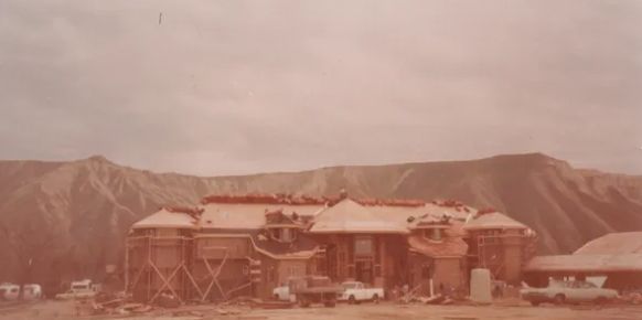 Snowy mountain lodge with red roofs and a cloudy sky in the background.