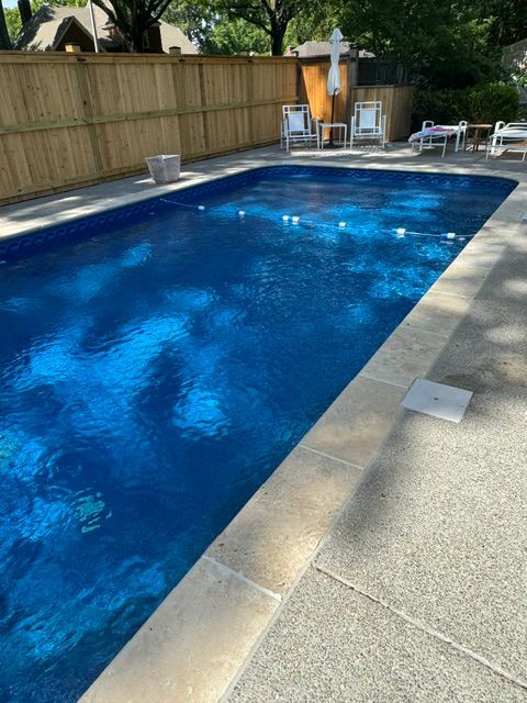 A large swimming pool surrounded by chairs and a wooden fence