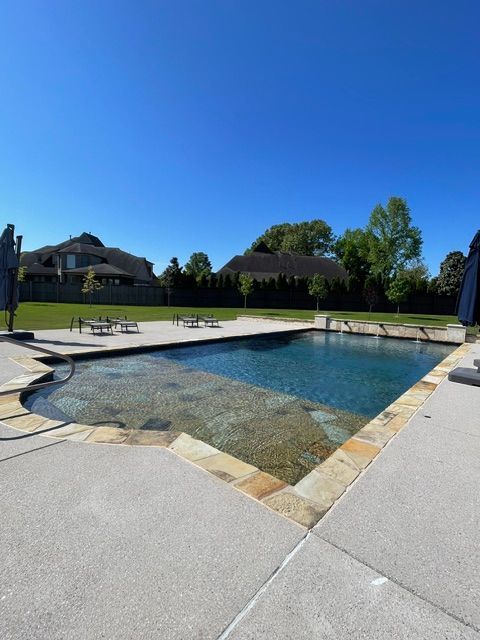 A large swimming pool with a house in the background