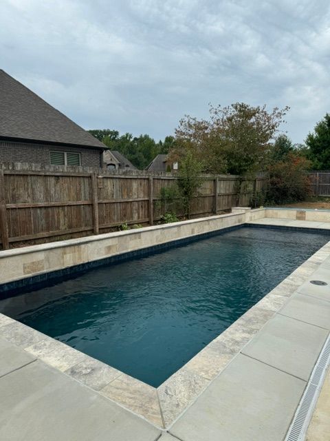 A large swimming pool with a wooden fence surrounding it