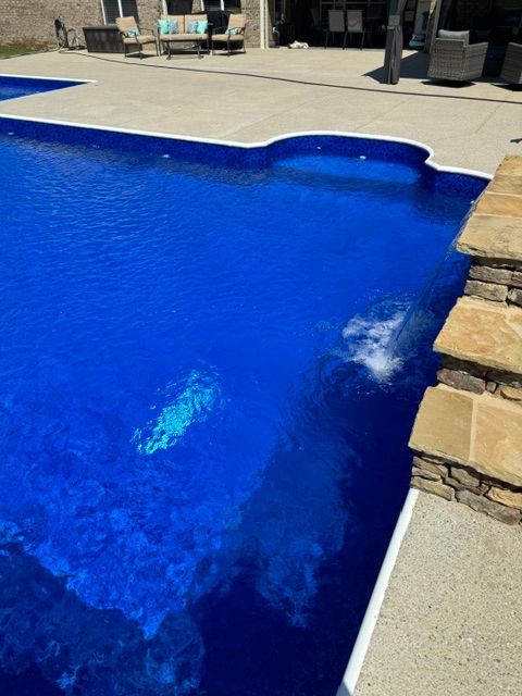 A blue swimming pool with a stone wall surrounding it
