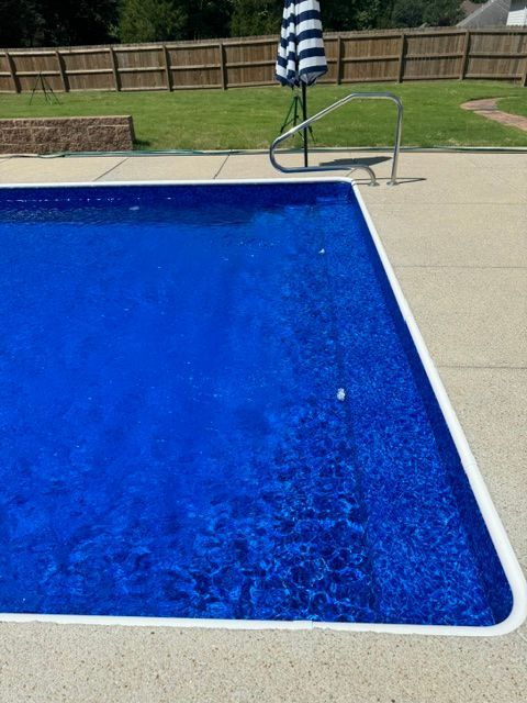 A blue swimming pool with a black and white striped umbrella