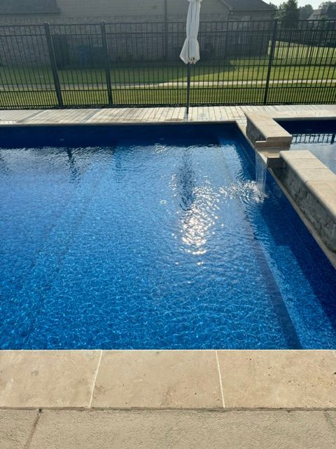 A large swimming pool with a white umbrella in the background