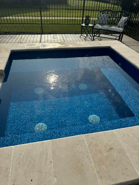 A swimming pool with blue tiles and a bench in the background.