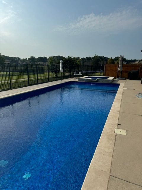 A large blue swimming pool with a fence around it