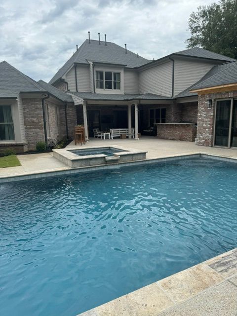 A large swimming pool is in the backyard of a house.