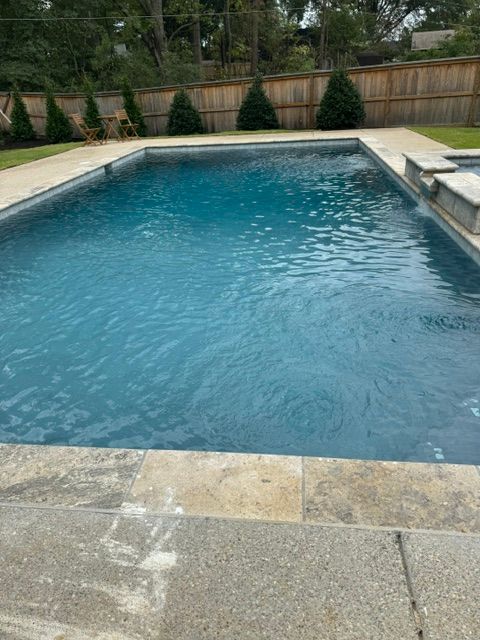 A large swimming pool filled with blue water in a backyard.