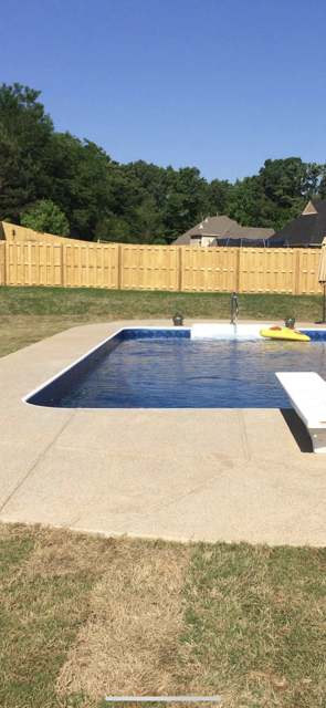 A large swimming pool in a backyard with a wooden fence.