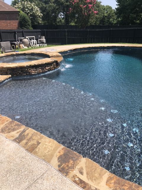 A large swimming pool with a hot tub in the middle