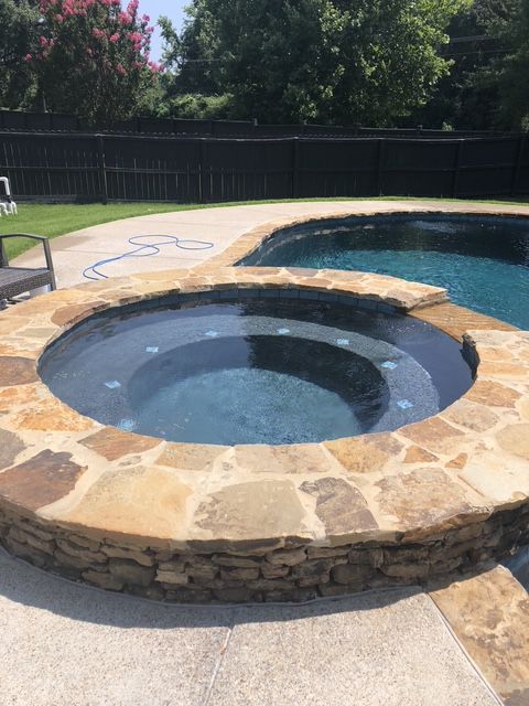 A swimming pool with a hot tub in the middle of it.