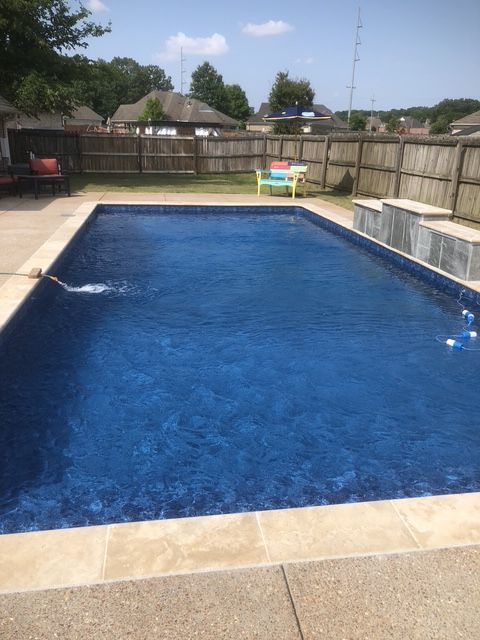 A large blue swimming pool with a fence in the background