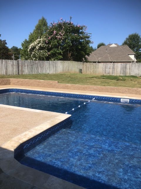A large swimming pool with a house in the background