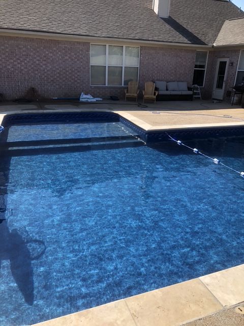A large swimming pool with a house in the background