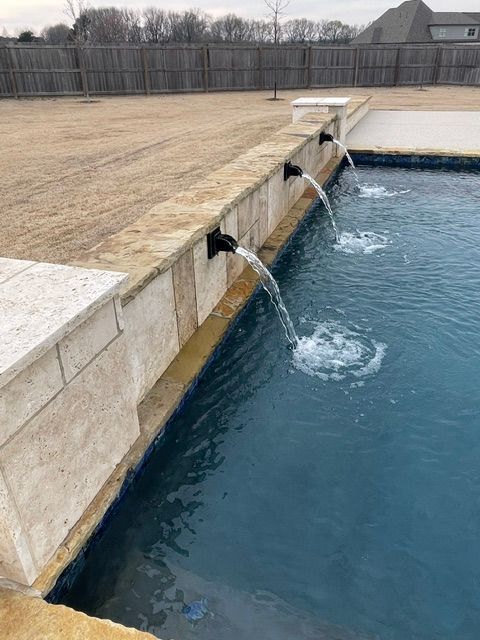 A swimming pool with two water fountains coming out of it.