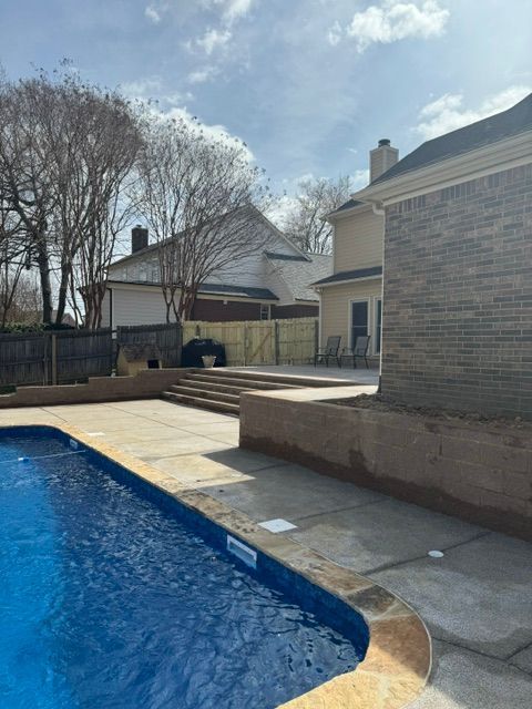 A large swimming pool is in the backyard of a house