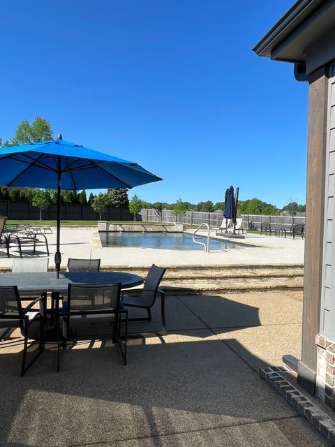 A patio with a table and chairs and a blue umbrella
