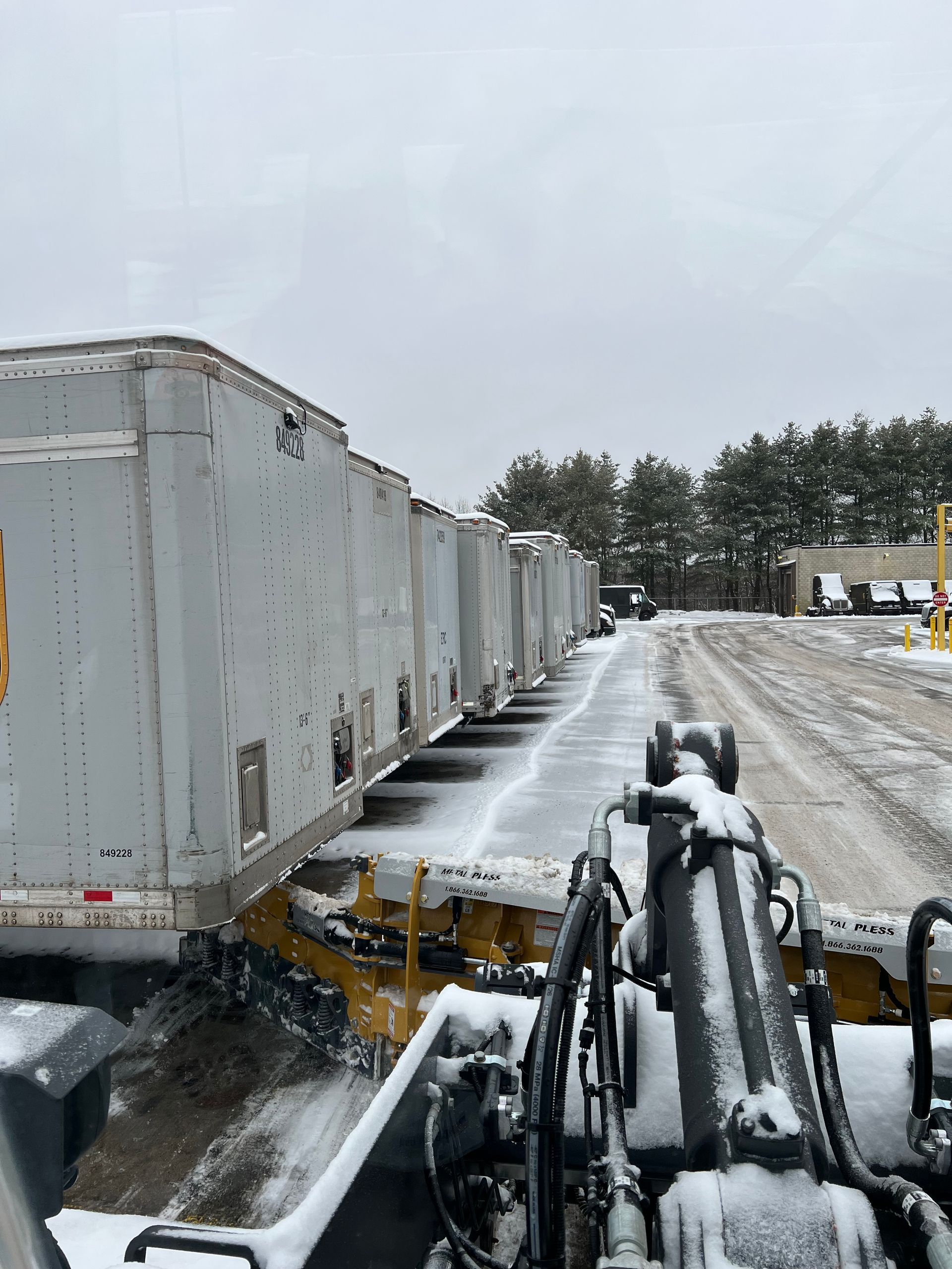 A row of semi trucks are parked in a snowy lot.