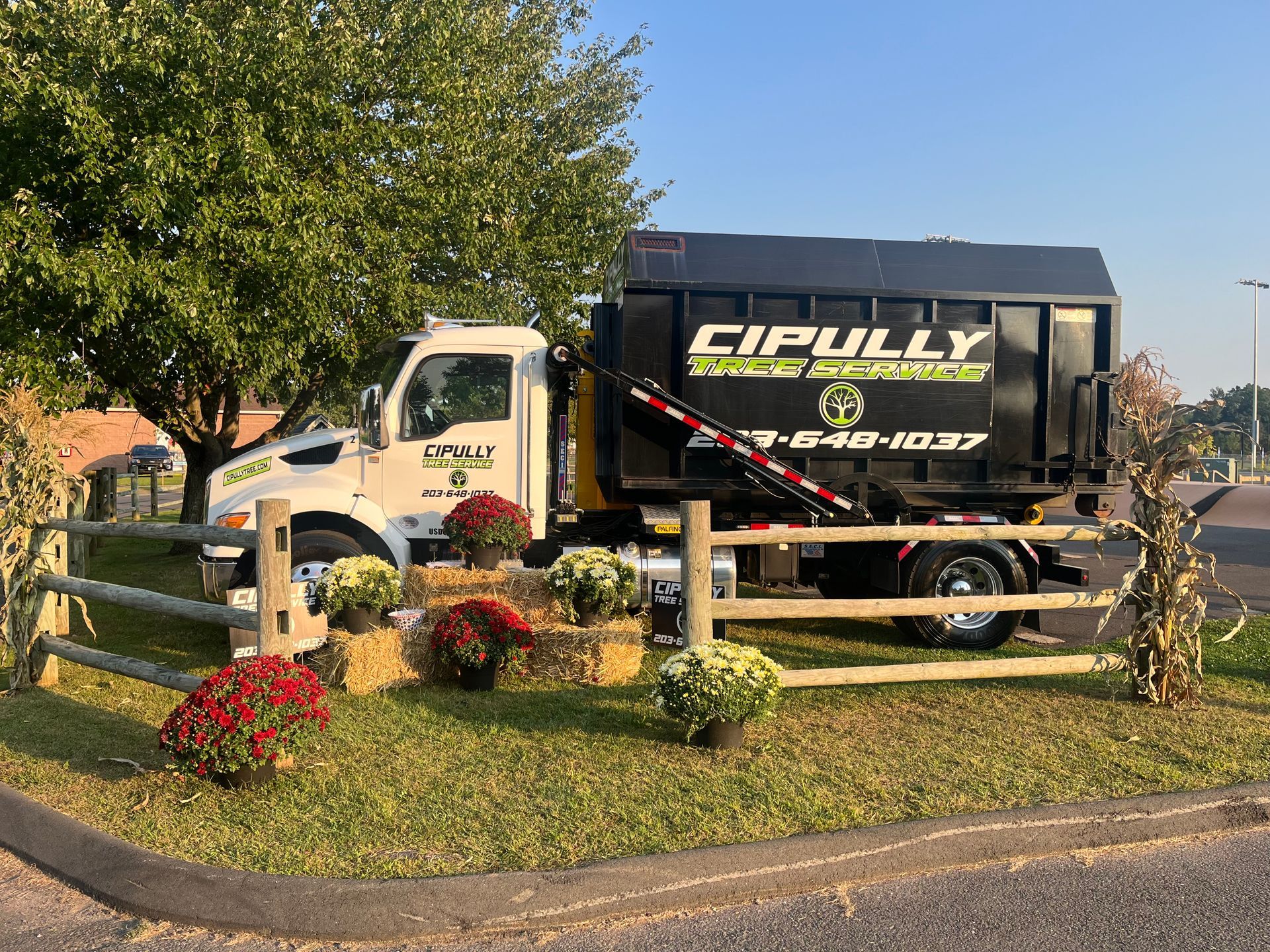 A dumpster truck is parked in front of a wooden fence.