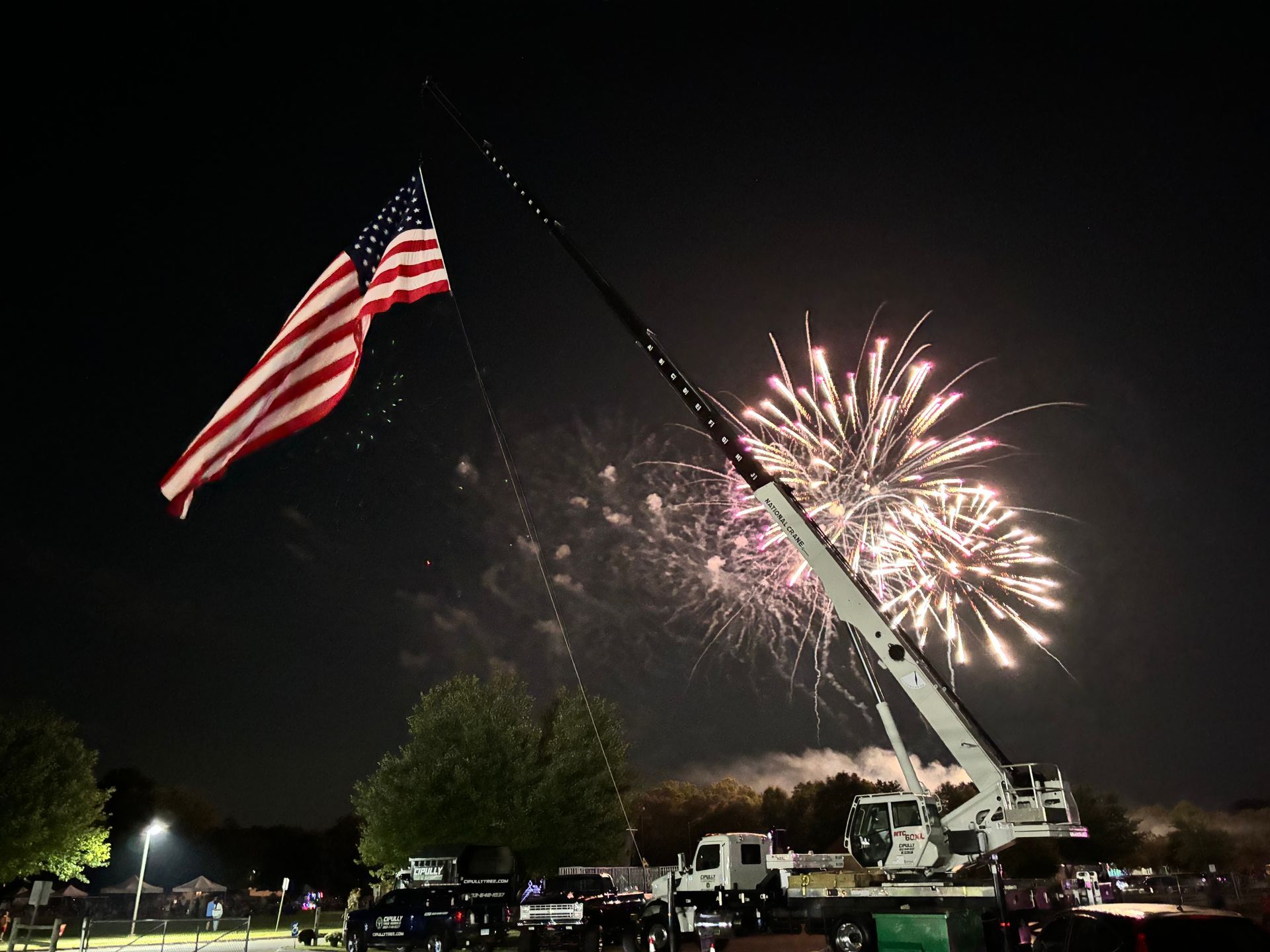An american flag is being raised in front of a fireworks display